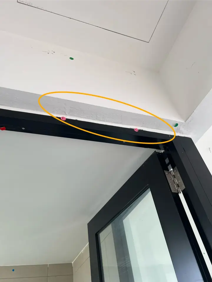 Gap between a door frame and the wall above a bathroom door, circled in amber