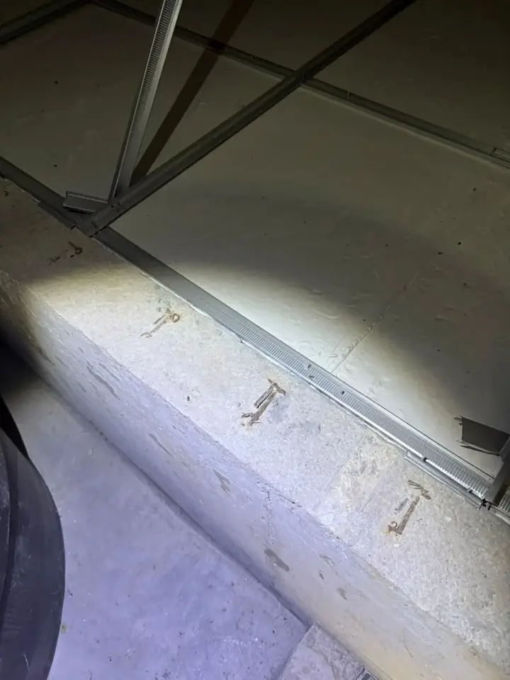 Exposed steel reinforcement on a concrete beam in a water tank area
