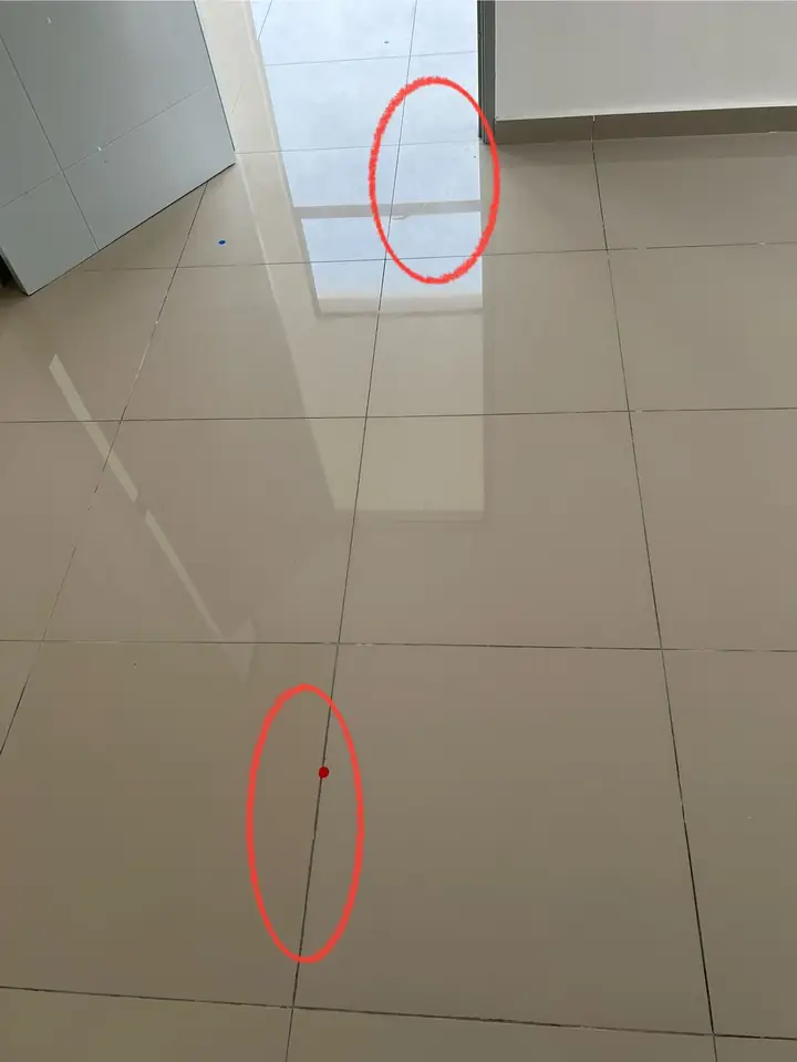 Crack through a floor tile, marked with red stickers and circled in red