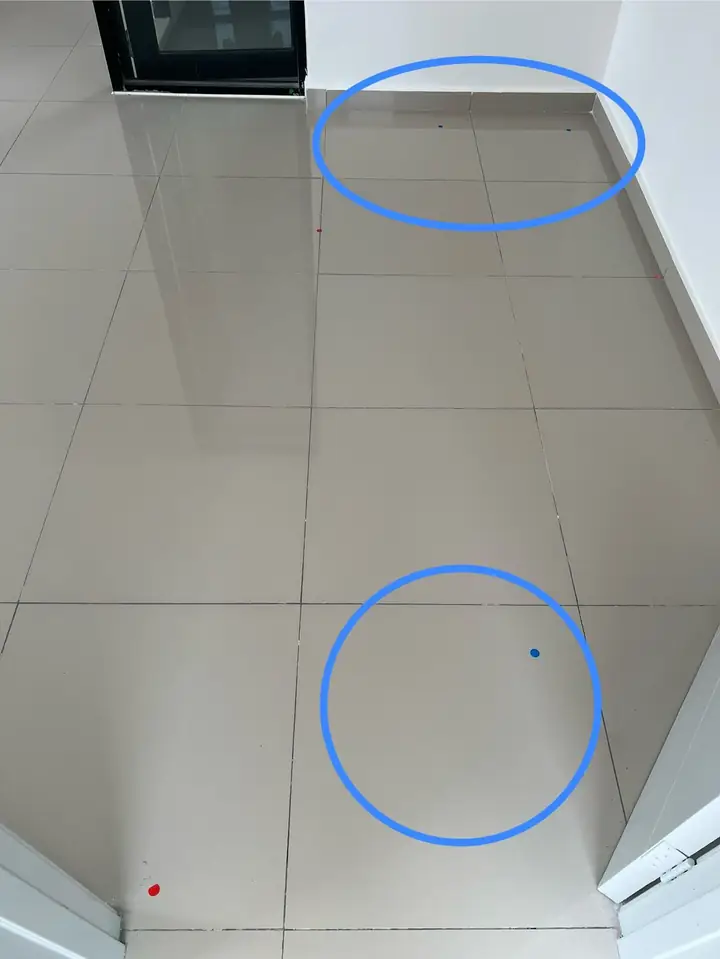Hollow floor tiles in a new bedroom, marked with small blue stickers and circled in blue