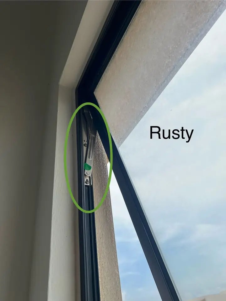 Rusty window hinge in a newly handed-over bedroom, circled in green