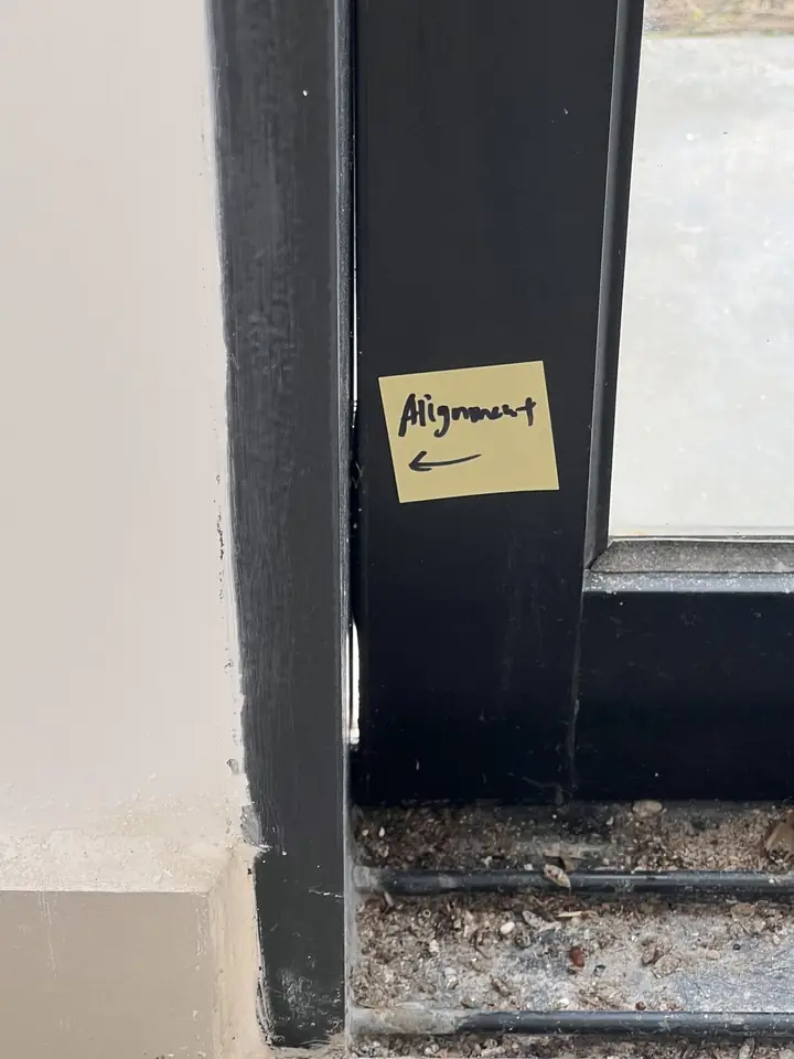 Sliding door frame out of alignment, with a handwritten note stuck to it